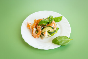 Fresh vegetable salad with shrimps and cucumbers on a green background