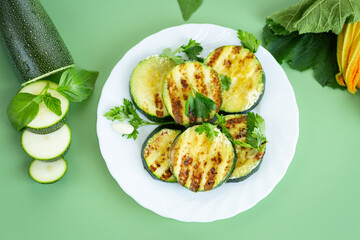 Grilled zucchini slices on a bright green background