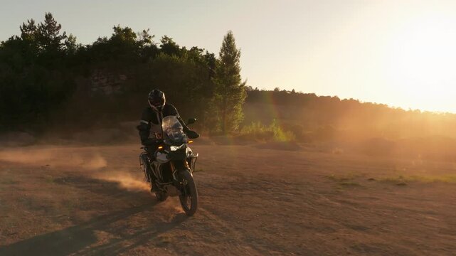 Slow motion shot of a rider on a motorcycle riding in dusty terrain