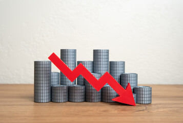 A stack of coins and a red arrow pointing down. Declining financial stability, loss of income, or...