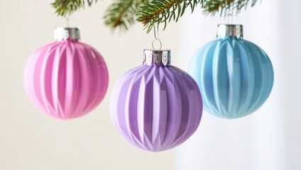 Obraz premium Vibrant and Elegant Decorative Ornaments in Pastel Pink, Lavender, and Blue Hanging from a Christmas Tree Branch, Adding Festive Charm to Seasonal Celebrations