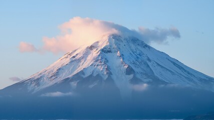 A majestic snow covered mountain with clouds cascading down its side