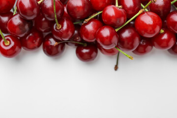 Fresh ripe cherries on white background, flat lay. Space for text