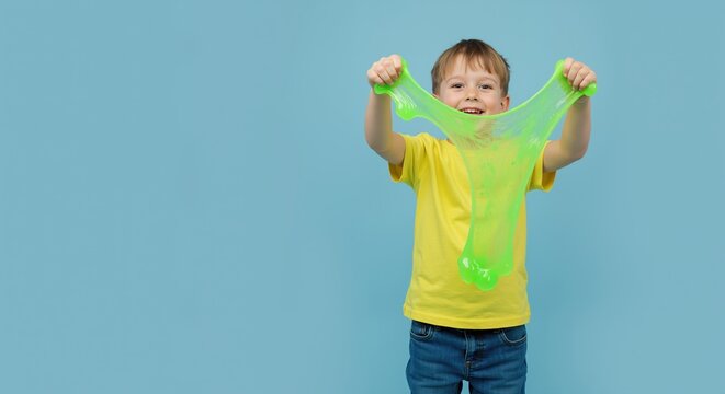 Happy boy playing with green slime against a blue background  