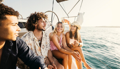 Four young friends are having fun while sailing on a sailboat on a sunny day