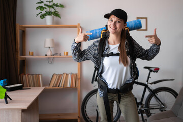 Smiling young female traveler hiker ready to trip with backpack pointing to herself with fingers...