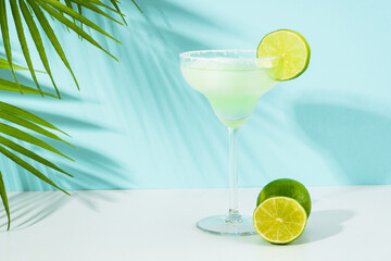 Margarita cocktail. Summer alcohol drink with silver tequila, liqueur, lime juice, sugar syrup, salt and ice on blue background.