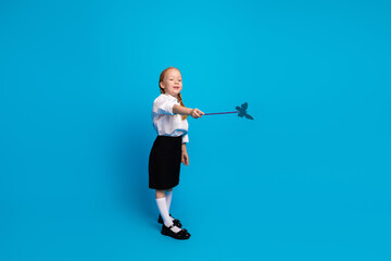 Adorable young schoolgirl with red pigtails poses confidently wearing a charming uniform on a...