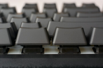 close-up macro view of black mechanical gaming keyboard keys, showing height and slope of the keys, designed for intense gaming or typing performance, side view in soft focus