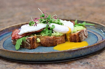 Avocado Toast with Poached Eggs, Bacon and Microgreens – Gourmet Breakfast Close-Up