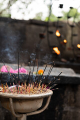 Incense burning in a pot with oil lamps in background at buddhist temple