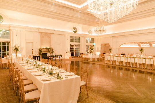 Elegant reception hall ready for celebration in warm evening light with floral decorations and twinkling chandeliers