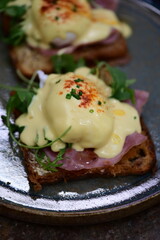 Eggs benedict with ham, rucola and cheese, closeup, serving breakfast menu