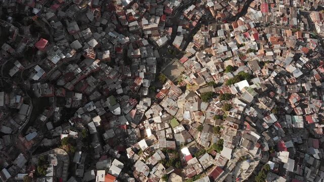 Drone shot of Comuna 13 in Medell&iacute;n, Colombia, featuring colorful murals, vibrant streets, and tourist activity. An iconic area known for its social transformation and urban street art.