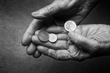 Hands of an elderly person with money, coins. Close-up of seniors hands holding and counting money.  Selective focus. Toned image, black and white