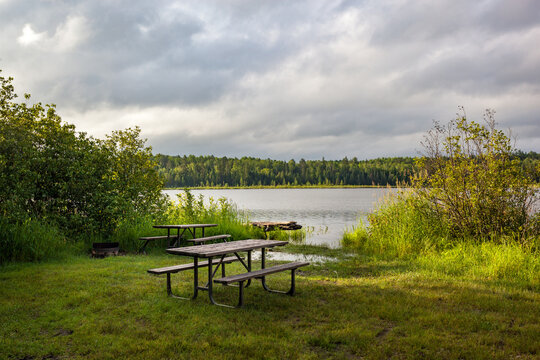 Wooden picnic tables at a grassy waterfront campsite near Temagami, Ontario, Canada