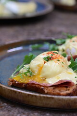 Eggs benedict with ham, rucola and cheese, closeup, serving breakfast menu