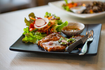 grilled pork steaks in black plate with spices at restaurant