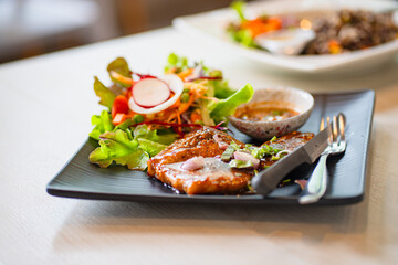 grilled pork steaks in black plate with spices at restaurant