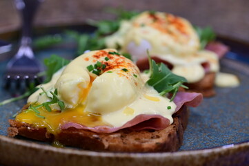 Eggs benedict with ham, rucola and cheese, closeup, serving breakfast menu
