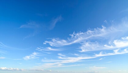 Fototapeta premium A bright blue sky with wispy, cirrus clouds stretching across the horizon on a clear day.