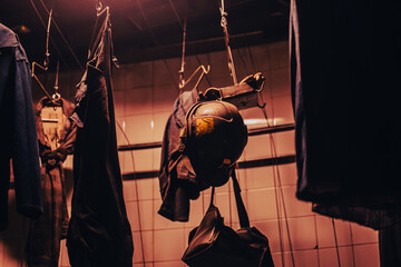 Mining equipment and workwear suspended from the ceiling in an authentic locker room. A miner's...