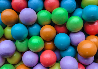 A vibrant and colorful overhead shot of numerous wooden or painted balls, tightly packed together, creating a lively full-frame texture.