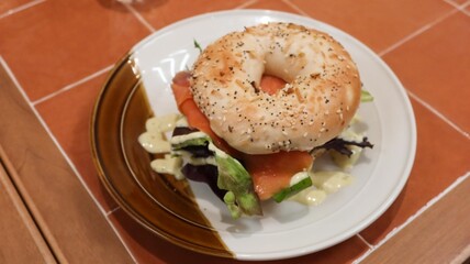 close up of a sesame and pumpkin seed bagel with lecttuce, smoked salmon and avocado on a plate