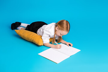 Young schoolgirl drawing with focus on creativity and education on a vibrant blue background