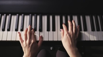 Close-up top view of woman's hands gently playing piano keys in soft light. Relaxing and inspiring slow motion video showing mindfulness, creativity and beauty of music with graceful delicate touch. - Powered by Adobe