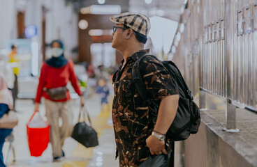 Side view Tourist asian man backpacker standing in the station waiting for train, people and travel concept.