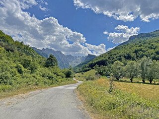 Picturesque road going into the mountains between green hills, summer landscape