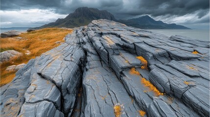 Grey layered rocks on a grassy hillside under dramatic sky