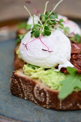 Avocado Toast with Poached Eggs, Bacon and Microgreens – Gourmet Breakfast Close-Up