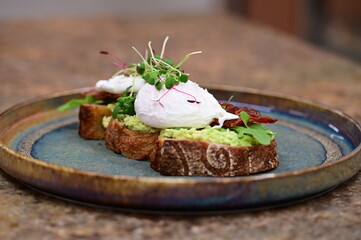 Avocado Toast with Poached Eggs, Bacon and Microgreens – Gourmet Breakfast Close-Up