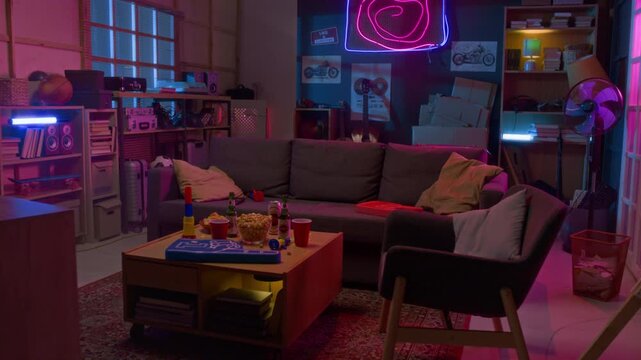 Wide angle shot of man cave room with big sofa facing TV and neon lights with posters on walls, copy space