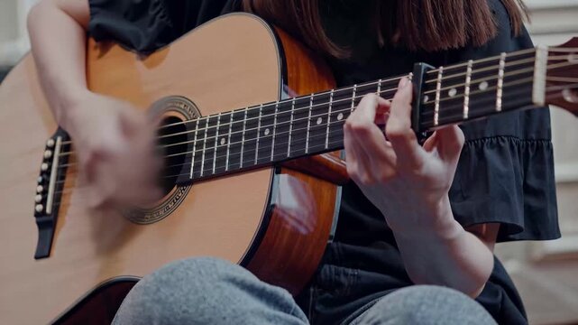 Woman playing the guitar. A woman is playing a guitar. A performer focused on the strings. A female guitarist lifestyle.