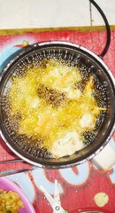 Close-up of traditional Indonesian bakwan frying in hot oil using an electric fryer