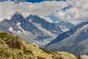 Fototapeta premium Beautiful mountain landscapes of the Alps on Tour du Montblanc hike. Green valley, snow summits and rocky peaks of Aiguilles de Chamonix and Montblanc. Summer sunny weather blue sky, trekking Alp hike