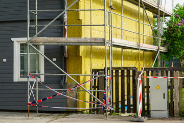 Home Wall Thermal Insulation Installation with Scaffolding and Safety Tape During Renovation