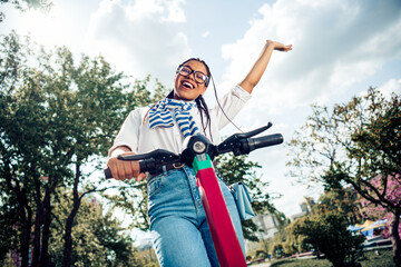 Young woman enjoying a spring day outdoors riding a scooter in a blooming park with a cheerful...