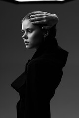 Black and white portrait of a thoughtful woman in dark clothing with hand on forehead, showing...