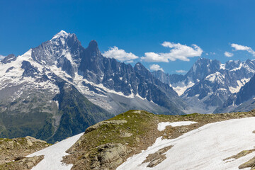 Fototapeta premium Beautiful mountain landscapes of the Alps on Tour du Montblanc hike. Green valley, snow summits and rocky peaks of Aiguilles de Chamonix and Montblanc. Summer sunny weather blue sky, trekking Alp hike