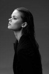 Black and white portrait of serious woman with wet hair looking sideways, wearing dark clothing,...