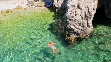 Beautiful Young Woman in Bikini Swims in Stara Baska Beach Krk Island, Croatia. Mediterranean Summer. Aerial Shot From Above. Blue Sea the Rocks  Mountains and Coastline Calm Sea With Clear Blue Water - Powered by Adobe