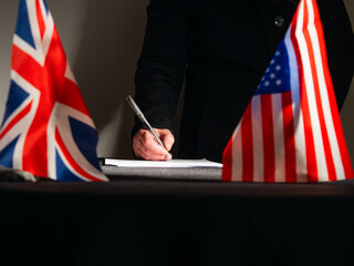 Hand signing a trade deal with American USA flag and British Union Jack