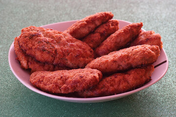 Crispy fried chicken tenders served on a white platter with a colorful background at a gathering