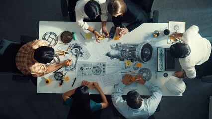 Top view of smart engineer team in casual cloth talking about turbine engine structure at table...