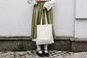 Young white woman holding black eco bag on arm shoulder or hand, street wall at background. city living female going on shopping to grocery store