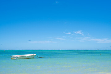 Beautiful landscape of Tropical Paradise - Belle Mare Beach with turquoise water. White boat in the Indian Ocean. Mauritius Island. Travel and vacation concept.